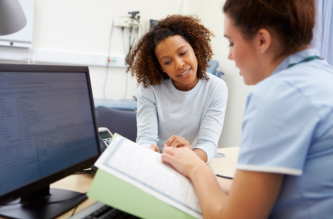 Stock photo of nurse reading files with patient